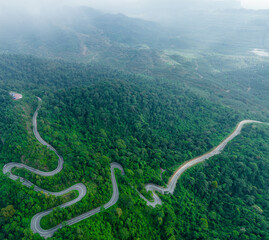 Aerial drone view of winding mountain road surrounded with greenery rainforest at Wang Kelian, Perlis, Malaysia.
