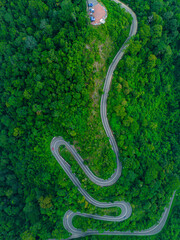 Aerial drone view of winding mountain road surrounded with greenery rainforest at Wang Kelian, Perlis, Malaysia.