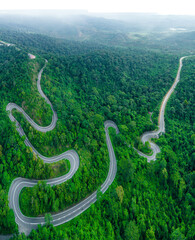 Aerial drone view of winding mountain road surrounded with greenery rainforest at Wang Kelian, Perlis, Malaysia.