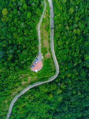 Aerial drone view of winding mountain road surrounded with greenery rainforest at Wang Kelian, Perlis, Malaysia.