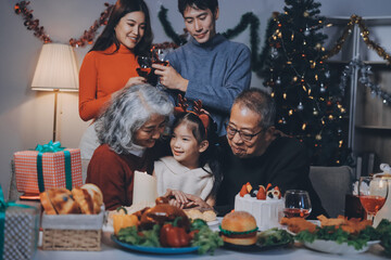 Multi-Generation Family Celebrate Christmas At Home Wearing Santa Hats And Antlers Opening Presents