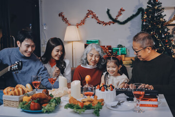 Multi-Generation Family Celebrate Christmas At Home Wearing Santa Hats And Antlers Opening Presents
