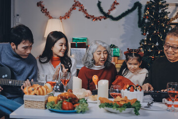 Multi-Generation Family Celebrate Christmas At Home Wearing Santa Hats And Antlers Opening Presents