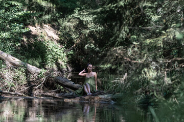 Beautiful young girl posing in a fast forest river in summer.