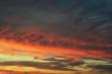 Obraz premium Sunset sky with vibrant hues of orange, pink, and purple. The clouds are dramatic and create a sense of awe and wonder. Concept of nature, beauty, and tranquility