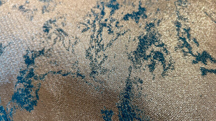 Close-up of a luxurious textured fabric with shimmering gold and teal patterns, showcasing intricate details and a refined aesthetic. Perfect for highlighting elegance and premium textile design.