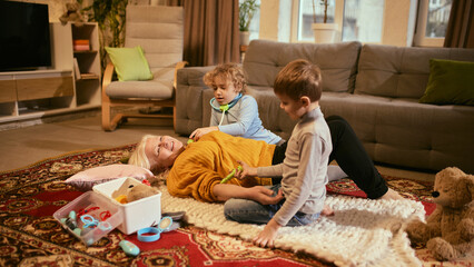 Children checking grandmother's health with toy medical kit, fostering playful learning about responsibility and healthcare basics. Concept of knowledge about healthy lifestyle and medicine.
