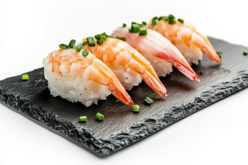 Four shrimp sushi pieces on a black slate plate, garnished with chives, isolated on white.