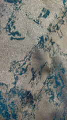 Detailed view of a textured fabric featuring shimmering gold and teal patterns in an abstract arrangement, perfect for showcasing luxury, elegance, and high-end textile design.