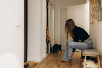 A woman puts on her shoes in the corridor of an apartment