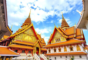 Naklejka premium A Thai Buddhist temple with ornate red and gold architecture, including a large roof with intricate designs and multiple levels (4)