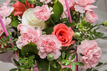 Pink carnations and roses on a white fabric background.