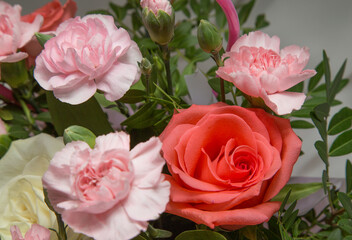 Pink carnations and roses on a white fabric background.