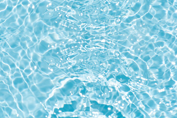 Blue water with ripples on the surface. Defocus blurred transparent blue colored clear calm water surface texture with splashes and bubbles. Water waves with shining pattern texture background.