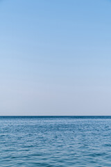 Obraz premium Blue sea surface with to the horizon. Sea waves with cloudy sky. Abstract background of water flow in ocean, sea, river, lake. Seascape wallpaper.