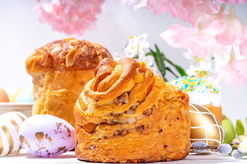 Easter baking background with traditional holiday cakes - kraffin, panettone, paska kulich, with Easter eggs, spring flowers on white wooden table, spring holiday Easter greeting card background
