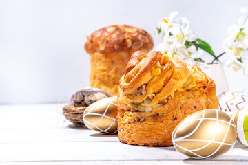 Easter baking background with traditional holiday cakes - kraffin, panettone, paska kulich, with Easter eggs, spring flowers on white wooden table, spring holiday Easter greeting card background