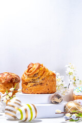 Happy Easter background with Easter eggs, panettone, spring flowers and pedestal podiums for product display, Easter holiday mockup on white wooden background