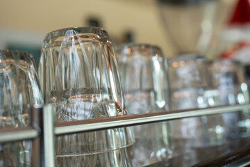 A clean glass lie upside down on a coffee machine in a cafe. Close up and selective focus.