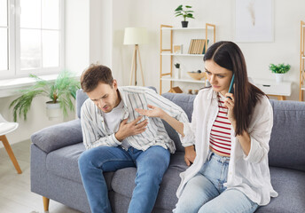 Man in his 30s at home having heart attack and suffering from chest pain, woman calling to doctor...