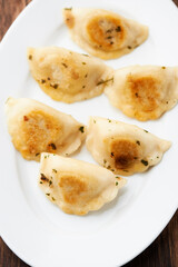 Dumplings with potato and cottage cheese stuffing (pierogi). Wooden background. Close up.