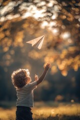 Child joyfully launches a paper airplane in a sunlit park surrounded by autumn foliage during late afternoon