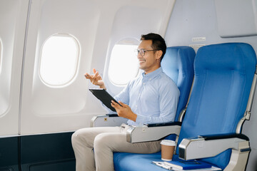 Young Asian executive excels in first class, multitasking with digital tablet, laptop and smartphone. Travel in style, work