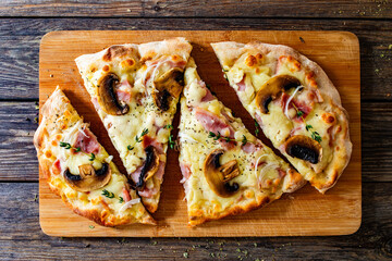 Roman Pizza with mozzarella cheese, boiled ham, onion, thyme and mushrooms on wooden table