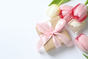 Beautiful fresh tulips with a gift box on color background
