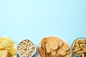 Various unhealthy snacks on color background