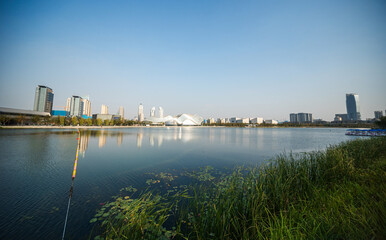 Fototapeta premium Serene Cityscape Reflected in Calm Waters with Lush Greenery