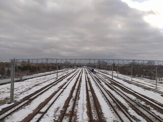Naklejka premium Railway tracks covered with snow on a cloudy day in winter. 