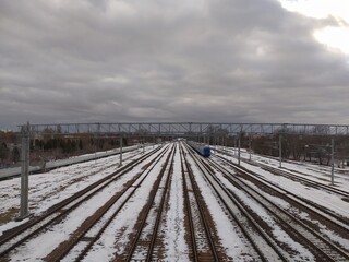 Obraz premium Railway tracks covered with snow on a cloudy day in winter.