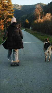 girl riding skateboard with a dog on the leash