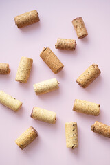 Many used wine corks arranged on pink background.