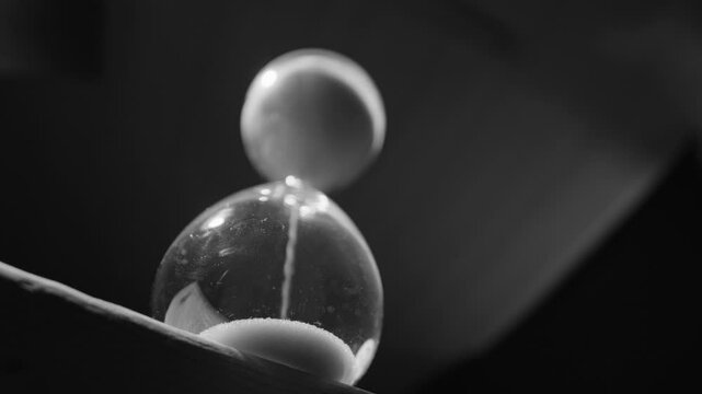 Hourglass with falling sand grains, black and white upward view slider shot