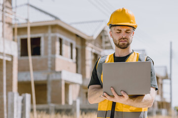 Construction worker Engineer male in safety vest helmet looking laptop computer at construction site