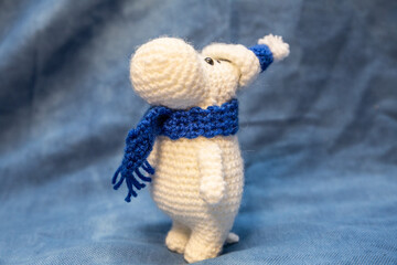 A soft toy in a hat with a pom-pom, a hand-knitted animal in a New Year's blue hat, stands on a blue background.