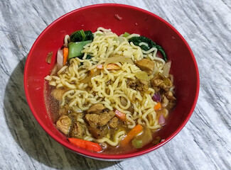 Chicken noodles with small pieces of chicken, pickles and green mustard greens.