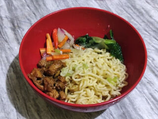 Chicken noodles with small pieces of chicken, pickles and green mustard greens.