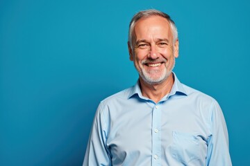 Obraz premium Confident Senior Businessman Portrait on Blue Background, Perfect for Corporate Websites, Marketing, and Professional Profiles