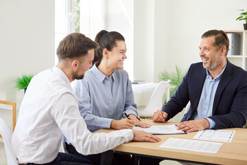 Happy married couple of clients engaged in a meeting or conversation with a real estate agent or...