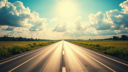 Naklejka premium Asphalt Road Stretching Towards a Bright Sunny Sky with Lush Green Fields on Either Side