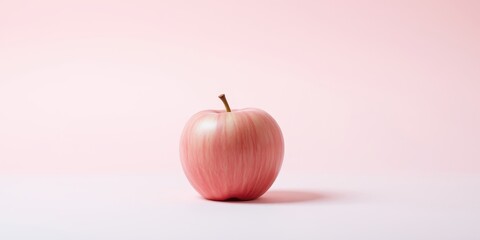 A single pink apple on a pale pink background, a minimalist fruit still life