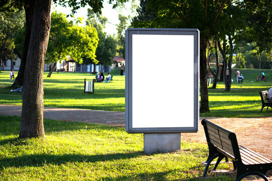 White vertical advertising poster on the grass. Blank banner in the park. Billboard in the city center mock up. LightPoster. 