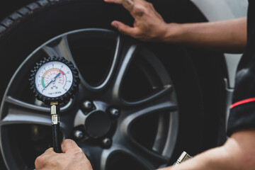 Hand car mechanic holding car tire pressure check equipment tool to checking low tire pressure...
