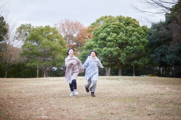 Fototapeta premium 冬の朝の公園で元気で楽しく遊んでいる子供姉妹の姿