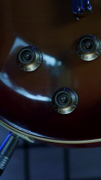 Turning volume and tone knobs on electric guitar at record studio.Vertical video
