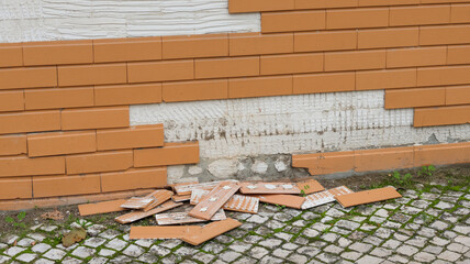 Broken tiles falling from building facade onto cobblestone street