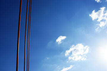 orange steel rope bridge in a row against the blue sky and clouds